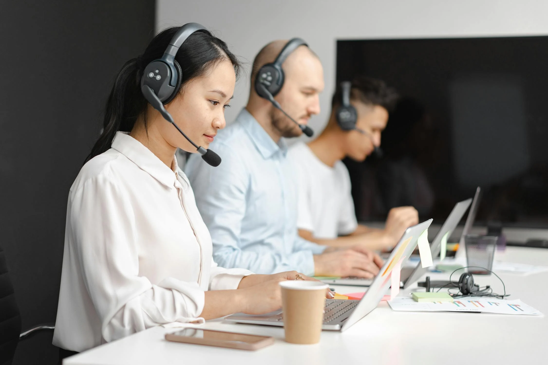 Three customer service agents with headsets responding to emails